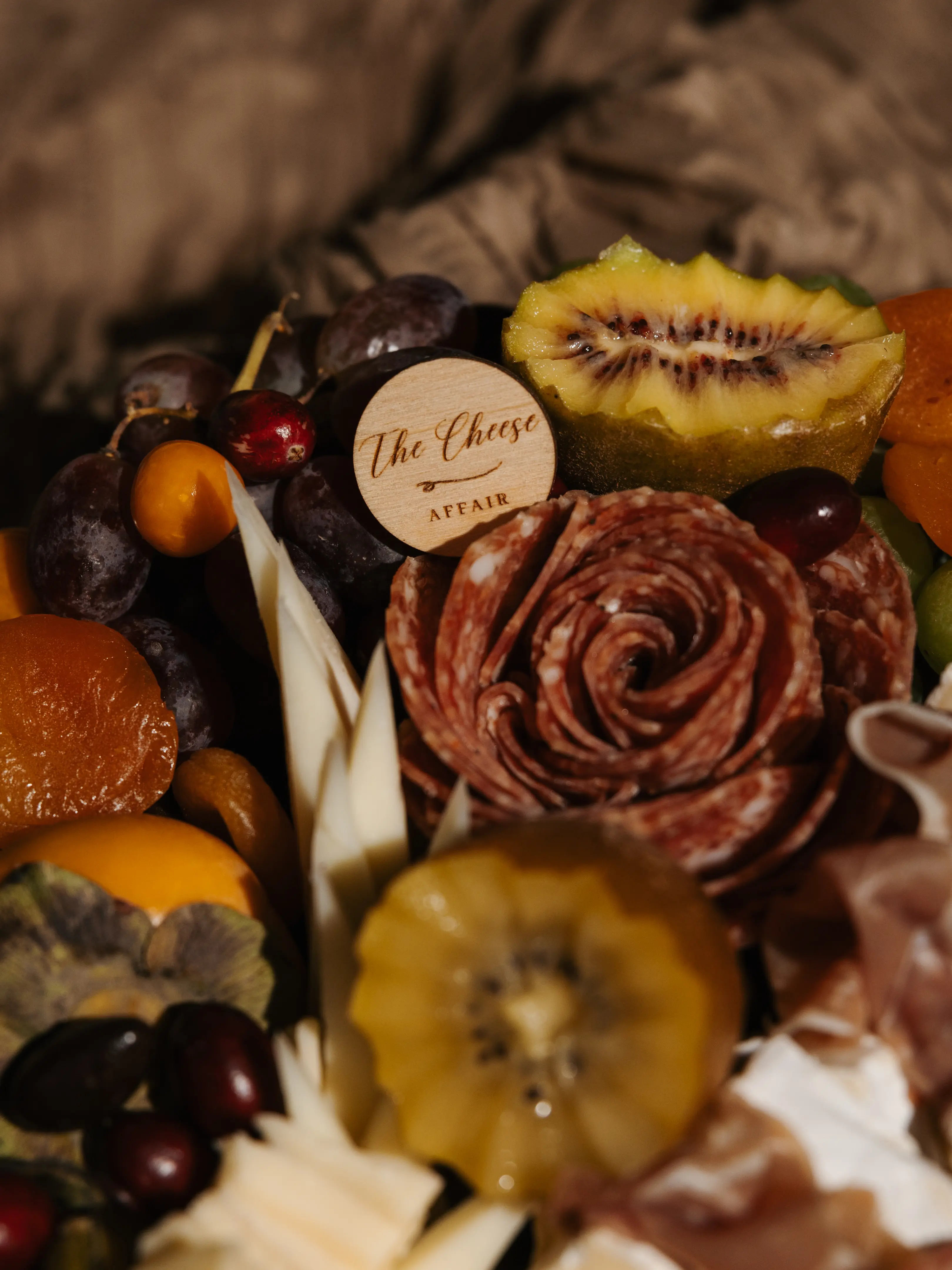 A close up detail of cheese, fruit, and board styling